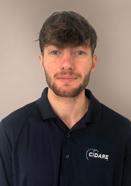 Hakim Boulil is a white man with brown hair and a beard, wearing a jacket and he's smiling.